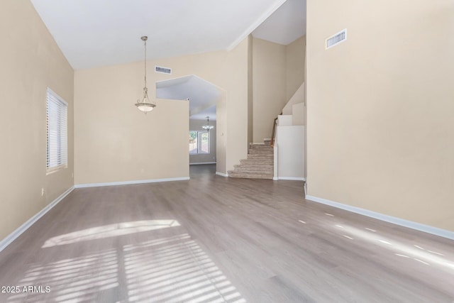 unfurnished living room featuring high vaulted ceiling, wood-type flooring, and an inviting chandelier