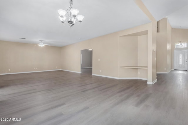 spare room with ceiling fan with notable chandelier, hardwood / wood-style flooring, and lofted ceiling