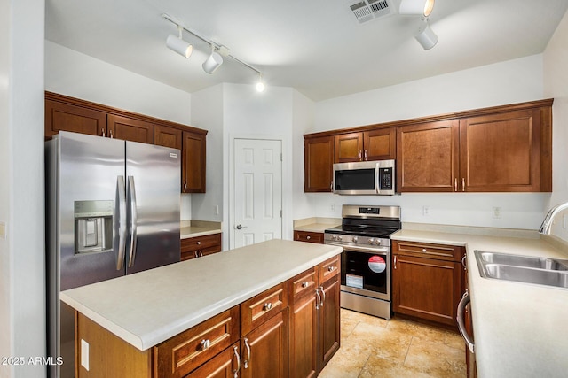 kitchen featuring sink, track lighting, stainless steel appliances, and a kitchen island