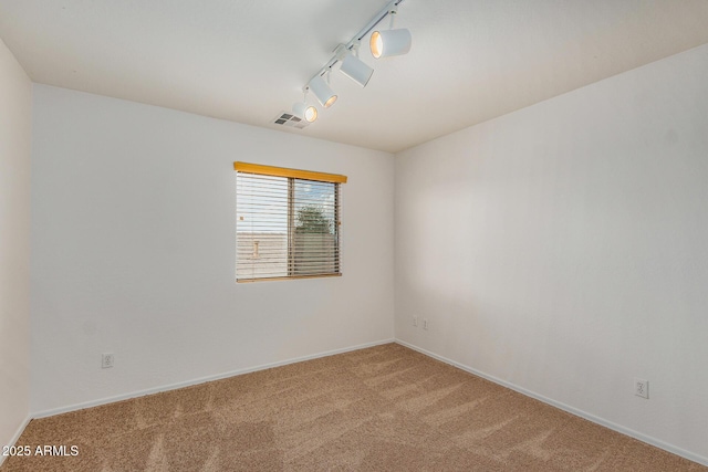 carpeted empty room with rail lighting