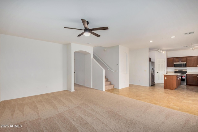 unfurnished living room featuring light colored carpet and ceiling fan