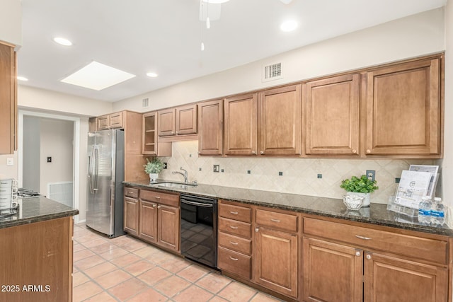 6025 N 10th Pl, Phoenix, AZ 85014 - kitchen with black dishwasher, freestanding refrigerator, brown cabinetry, dark stone counters, and decorative backsplash