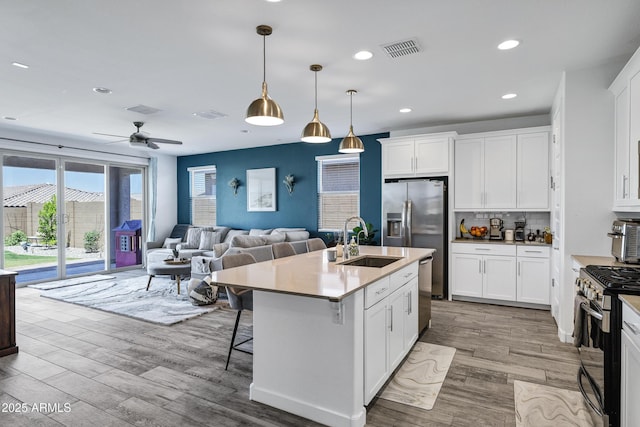 1652 W Estes Way, Phoenix, AZ 85041 - kitchen with stainless steel appliances, wood finished floors, recessed lighting, backsplash, and white cabinets