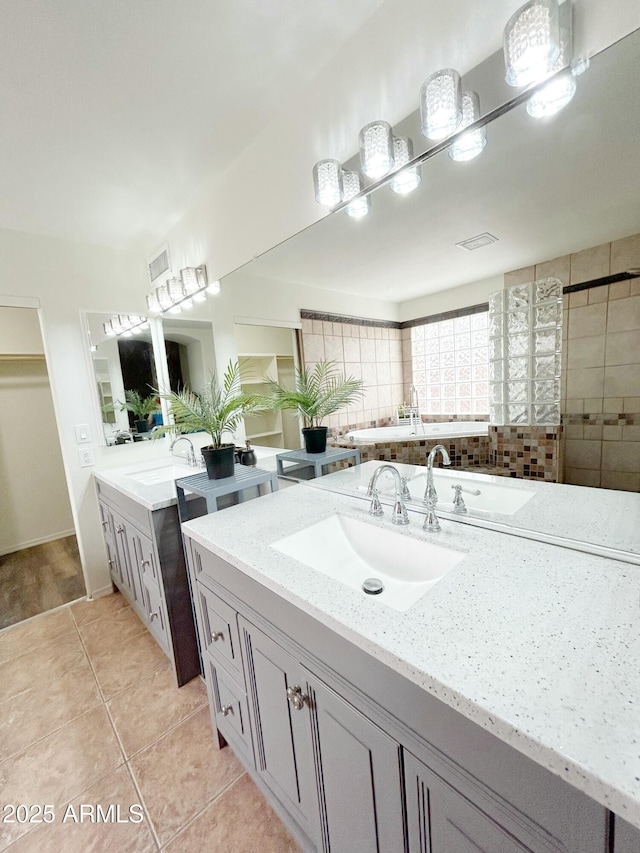 full bath featuring tile patterned flooring, visible vents, two vanities, and a sink