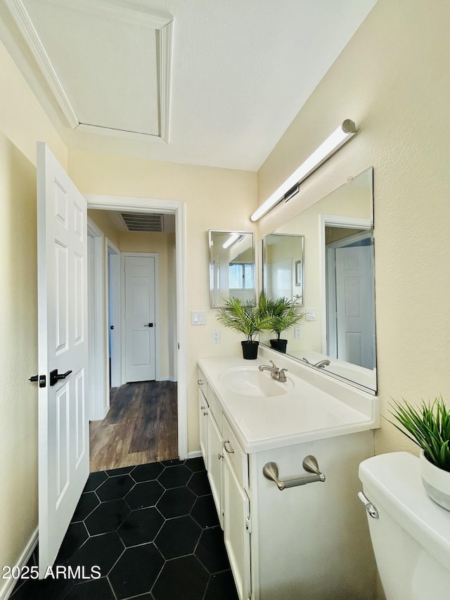 half bathroom featuring visible vents, toilet, vanity, and tile patterned flooring