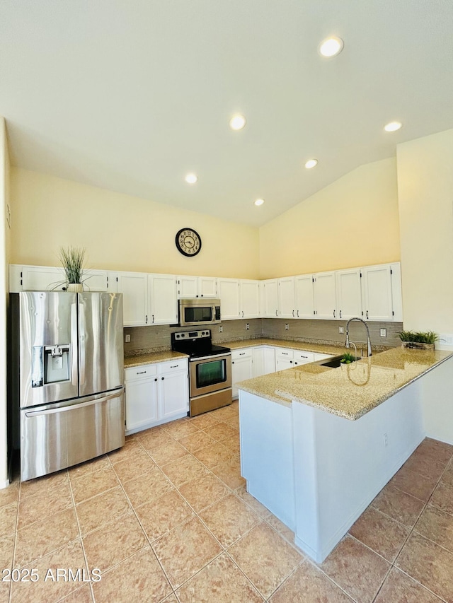 kitchen with a peninsula, white cabinets, appliances with stainless steel finishes, and a sink