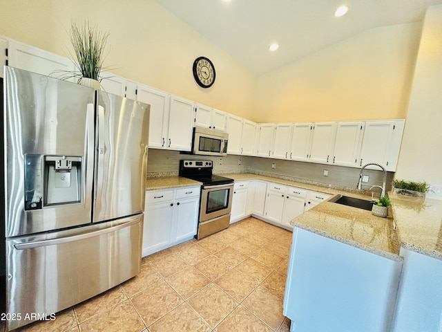 kitchen featuring light stone counters, white cabinets, stainless steel appliances, and a sink