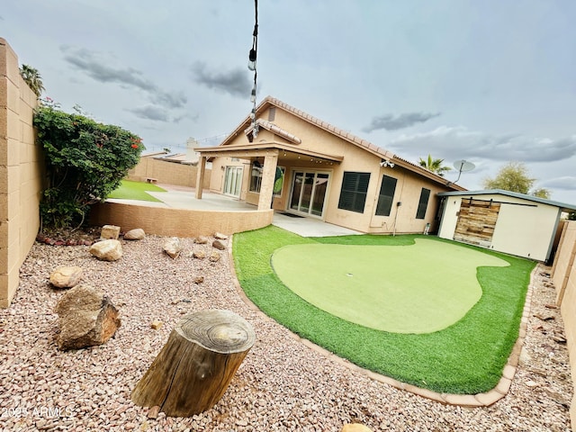 rear view of house featuring a storage unit, stucco siding, a patio, a fenced backyard, and an outdoor structure