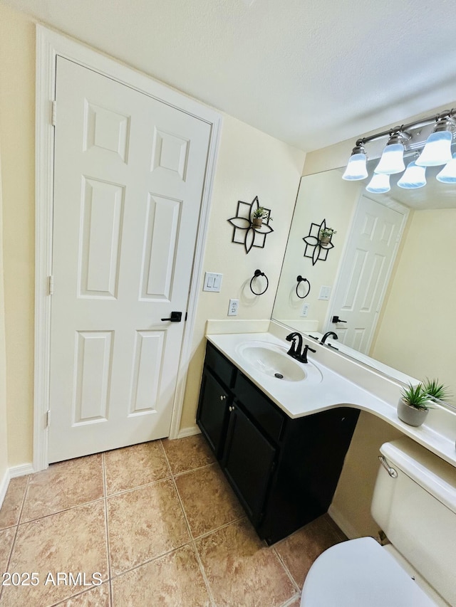 half bathroom featuring vanity, tile patterned floors, toilet, and a textured ceiling