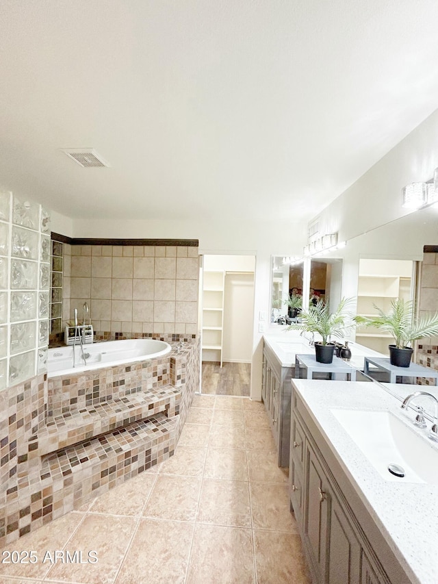 full bathroom with a garden tub, visible vents, tile patterned floors, and a sink