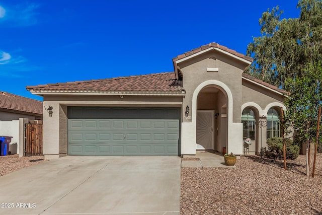mediterranean / spanish-style home with stucco siding, a tiled roof, fence, concrete driveway, and an attached garage