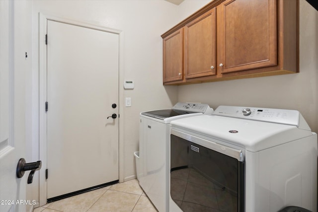 washroom with cabinets, washer and clothes dryer, and light tile patterned flooring