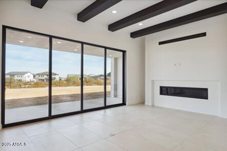 unfurnished living room featuring beamed ceiling and a glass covered fireplace