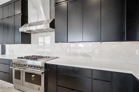 kitchen featuring modern cabinets, light countertops, wall chimney exhaust hood, and double oven range