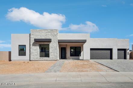 view of front of property featuring decorative driveway, a garage, stone siding, and stucco siding