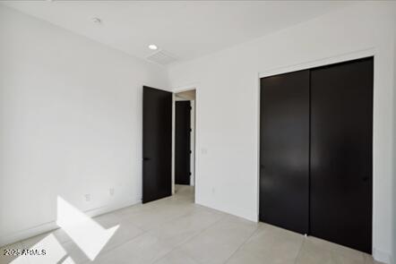 unfurnished bedroom with tile patterned flooring and a closet