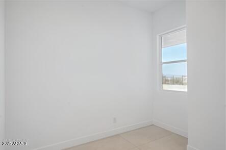 empty room featuring light tile patterned floors and baseboards