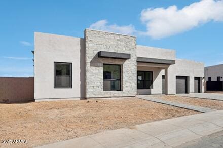 view of front facade featuring a garage, stone siding, concrete driveway, and stucco siding