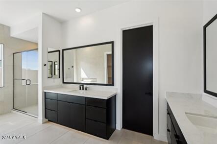 bathroom featuring a shower stall, two vanities, recessed lighting, and a sink