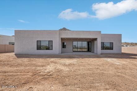 rear view of house featuring stucco siding and fence