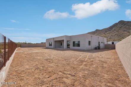 rear view of house featuring a fenced backyard, a mountain view, and stucco siding