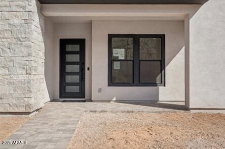 doorway to property with stucco siding and stone siding