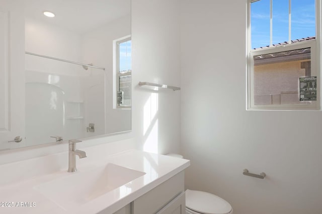 bathroom with walk in shower, vanity, and toilet