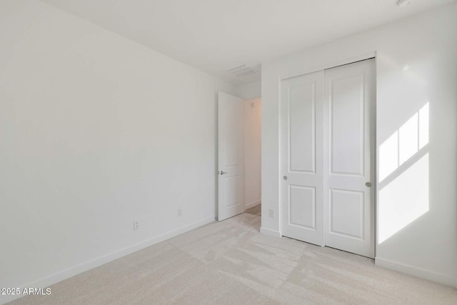 unfurnished bedroom with a closet and light carpet