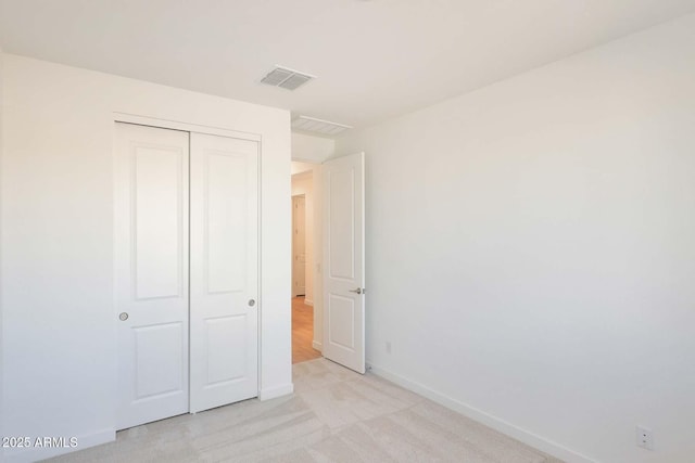 unfurnished bedroom with light colored carpet and a closet