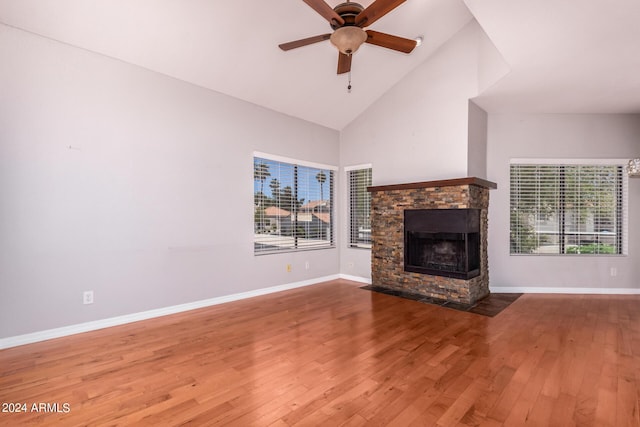 unfurnished living room with hardwood / wood-style floors, a stone fireplace, a healthy amount of sunlight, and ceiling fan