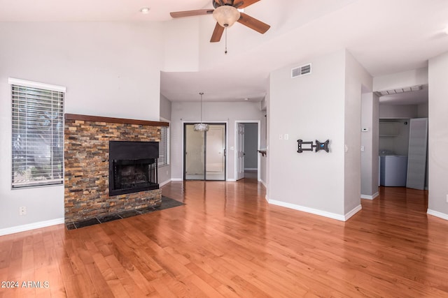 unfurnished living room featuring washer / dryer, vaulted ceiling, a multi sided fireplace, hardwood / wood-style flooring, and ceiling fan