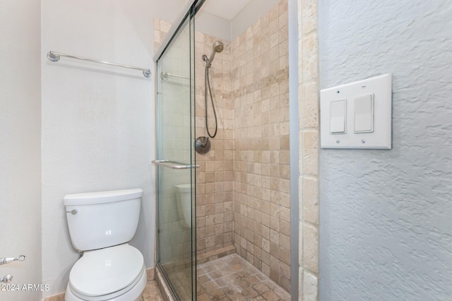 bathroom featuring toilet and a shower with door