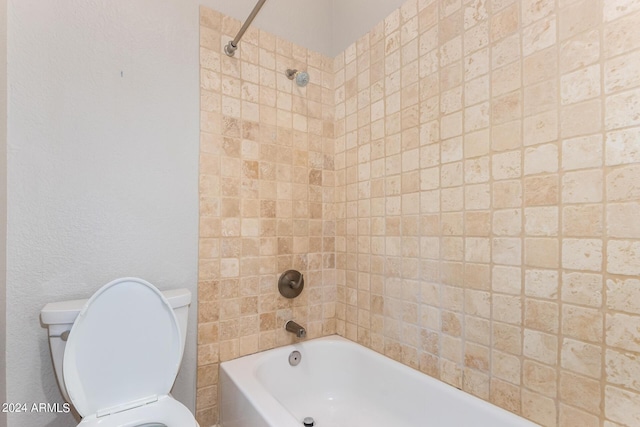 bathroom with tiled shower / bath combo and toilet