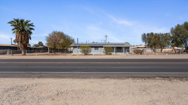 view of front of property with fence and roof mounted solar panels