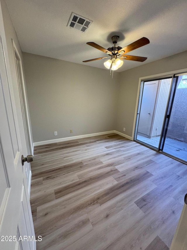 spare room featuring baseboards, ceiling fan, visible vents, and wood finished floors
