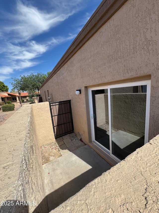 view of side of home with a gate and stucco siding