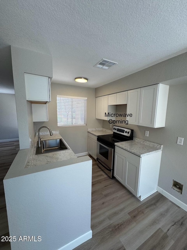 kitchen with visible vents, stainless steel electric range, a textured ceiling, a sink, and light wood finished floors