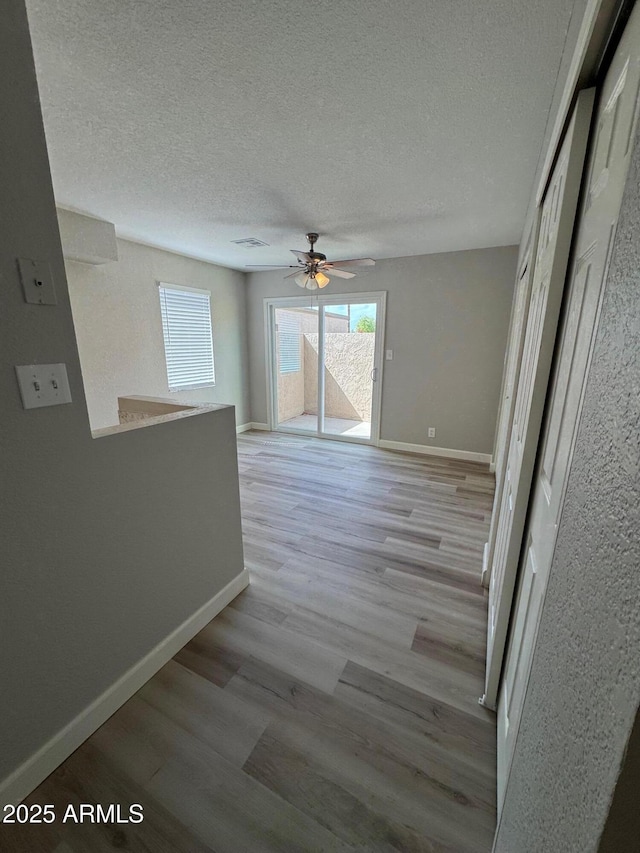 interior space with a textured ceiling, baseboards, and light wood-style floors