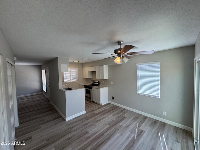 kitchen featuring a ceiling fan, a textured ceiling, a sink, and stainless steel range with electric stovetop