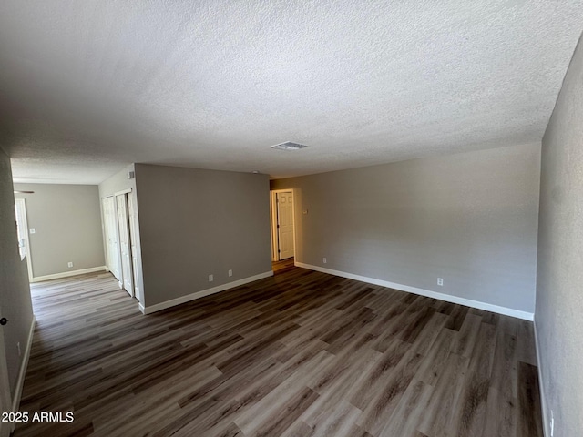 unfurnished room featuring baseboards, a textured ceiling, and dark wood-style floors
