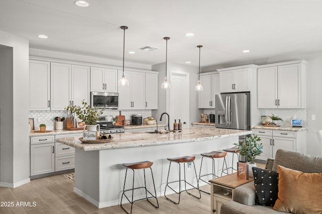 3505 W Verde River Rd, San Tan Valley, AZ 85144 - kitchen with light wood-style floors, a kitchen bar, tasteful backsplash, visible vents, and stainless steel appliances