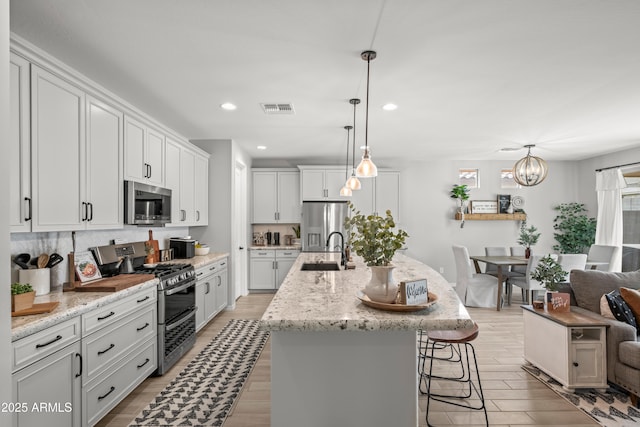 3505 W Verde River Rd, San Tan Valley, AZ 85144 - kitchen with light wood-type flooring, visible vents, a sink, stainless steel appliances, and decorative backsplash