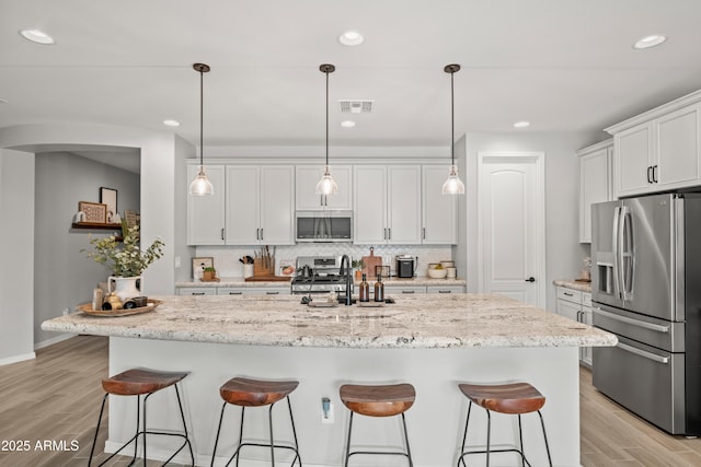3505 W Verde River Rd, San Tan Valley, AZ 85144 - kitchen with visible vents, appliances with stainless steel finishes, a kitchen bar, and light wood finished floors