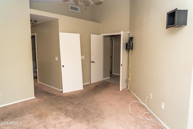 unfurnished bedroom with carpet flooring and a towering ceiling