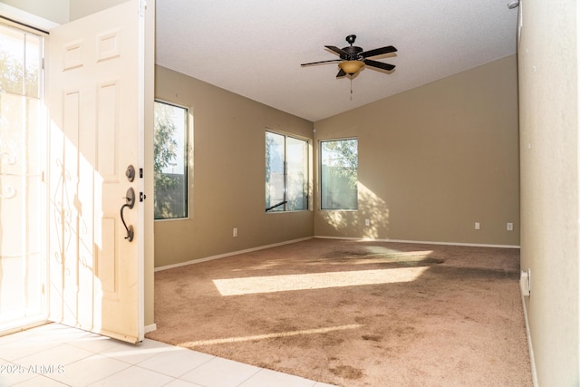 carpeted empty room featuring ceiling fan, vaulted ceiling, and a textured ceiling