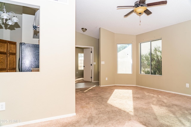 carpeted empty room with lofted ceiling and ceiling fan with notable chandelier