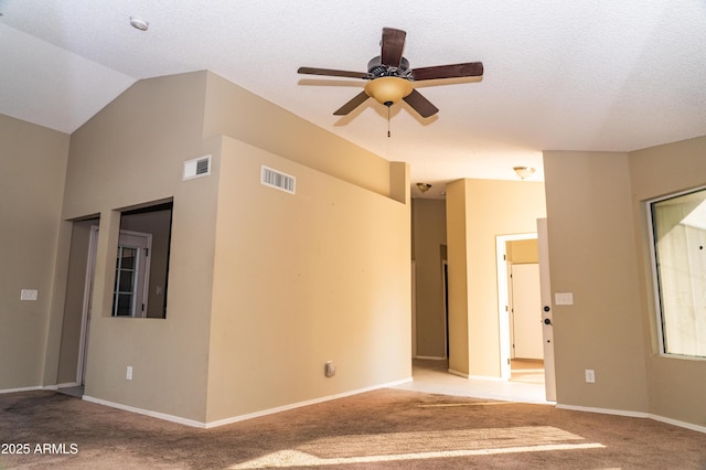 carpeted spare room with ceiling fan, vaulted ceiling, and a textured ceiling