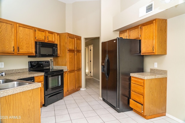 kitchen with light tile patterned flooring, sink, a high ceiling, and black appliances