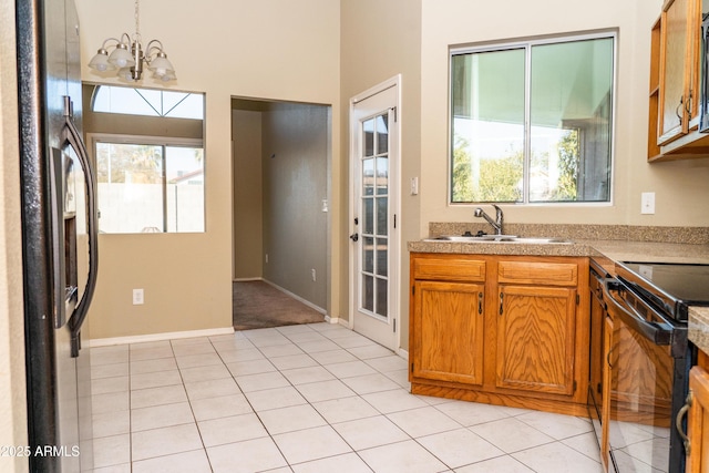 kitchen with sink, an inviting chandelier, hanging light fixtures, light tile patterned floors, and black appliances