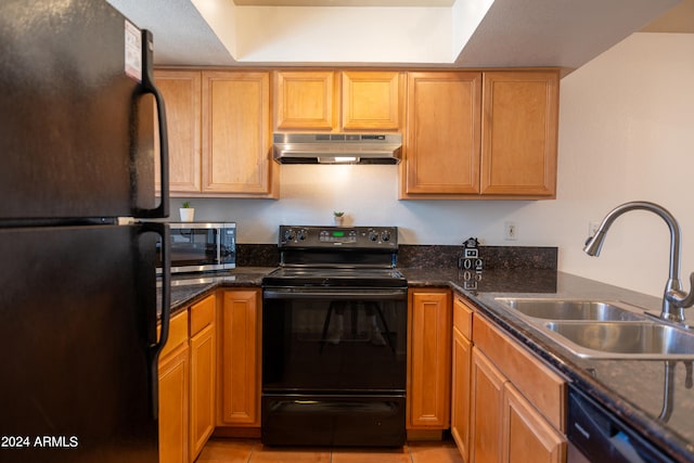 kitchen with dark stone countertops, black appliances, light tile patterned floors, and sink